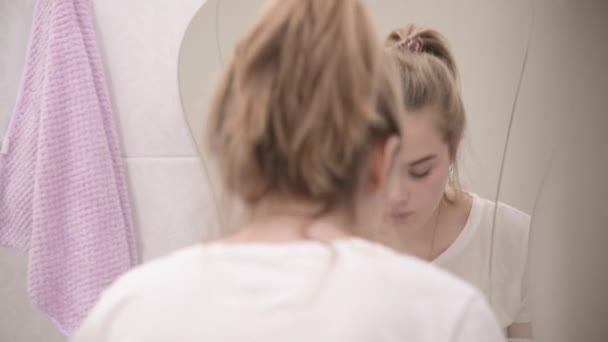 매력적 인 젊은 여자는 욕조에서 물로 얼굴을 닦는다. 좋은 아침 절차. 아침 생활. 하얀 가로등 화장실. — 비디오
