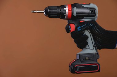 Eldiven giymiş bir kadının yakın plan fotoğrafı kahverengi arka planda bir tornavida tutuyor. Uzay stüdyosu görüntüsünü kopyala