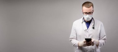 SMS için panoramik arka plan, üniformalı genç erkek doktor telefona bakıyor, stüdyo çekimi