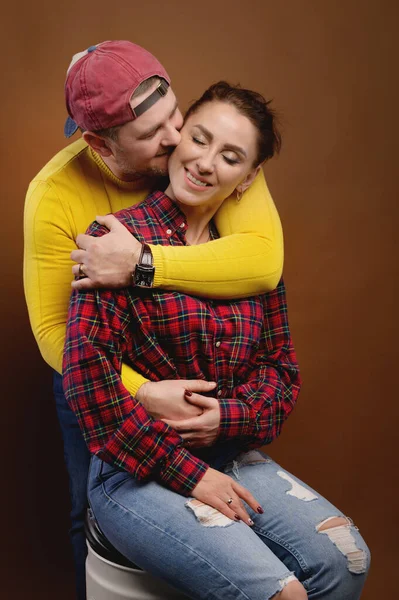 Καυκάσιο παντρεμένο ζευγάρι αγκαλιάζει και φιλάει μάτια κλειστά. Casual στυλ και φωτεινά ρούχα ενός συνηθισμένου 30-year-old πορτρέτο στούντιο ζευγάρι — Φωτογραφία Αρχείου