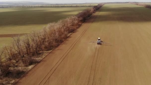 Luchtfoto Landbouwmachines spuiten insecticiden op een geploegd veld. landbouw natuurlijke seizoensgebonden voorjaar werken. Sproeien van landbouwtrekkers in het veld met een sproeiapparaat — Stockvideo