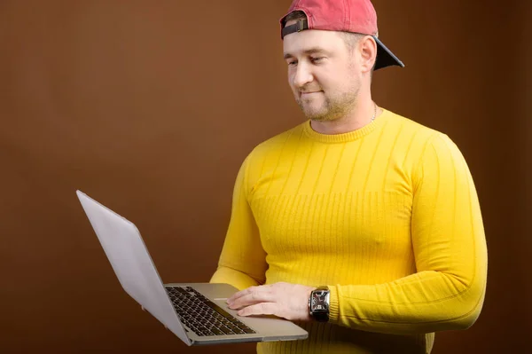 Een portret van een gefocuste blanke man met een laptop in zijn handen staat in de studio en kijkt aandachtig in de laptop. Het concept van het gebruik van pc en mobiele toegang op afstand tot diensten — Stockfoto