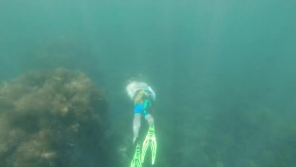 Pandangan bawah air dari seorang pria Kaukasia muda bertopeng dengan sirip dan dengan snorkel berenang di air laut transparan pada kedalaman. Freediving dalam gerak lambat — Stok Video