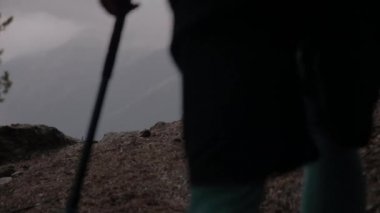 Dağların bulutlu havasında, akşamları ormandan çıkan uzun saçlı genç bir adamın arka görüntüsü. Seyahat ve seyahat.