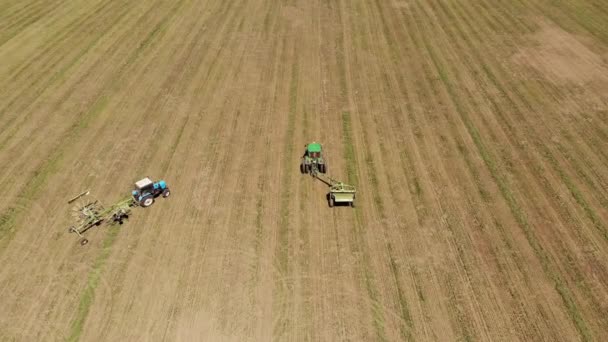 Utsikt over en traktor med en gressklipper, klipper gresset på et tomt jorde. Feltarbeid og vedlikehold gjennom hele året – stockvideo