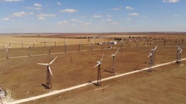 Rüzgar türbinlerinin hava görüntüsü sarı alanlar arasında temiz rüzgar enerjisi üretiyor. Rüzgârlı bozkırlarda yenilenebilir enerji üretimi.