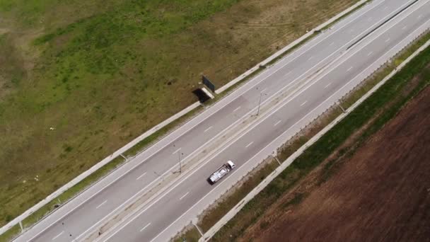 Widok z lotu ptaka na podmiejski tor samochodowy z kilkoma jadącymi samochodami. Koncepcja podmiejskiej infrastruktury drogowej. Ciepły letni dzień. Miękkie światło. — Wideo stockowe