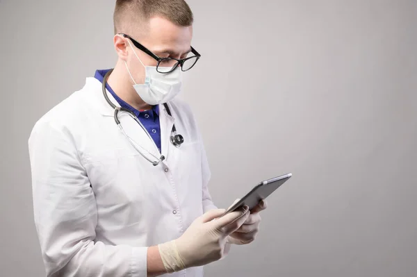 Фон для текста, молодой мужчина-врач в форме смотрит в телефон, студийный снимок — стоковое фото