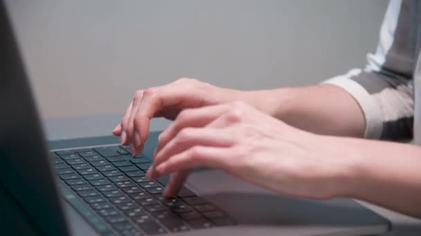 Primer plano Caucásico joven escribiendo con los dedos en el teclado portátil en la mesa de la cocina en casa. — Vídeos de Stock