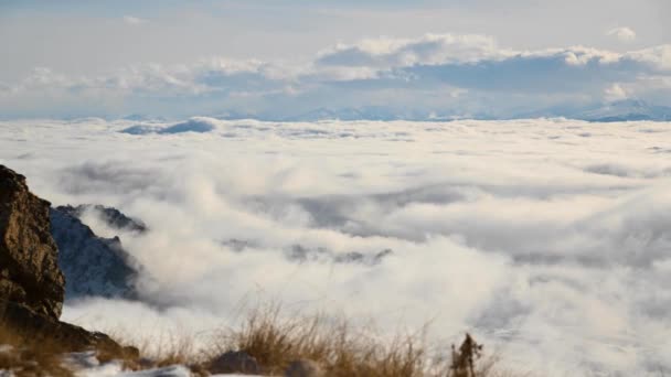 Un lapso de tiempo de invierno diurno en lo alto de las montañas, las nubes están cayendo de rocas épicas. Flujo de nubes — Vídeos de Stock
