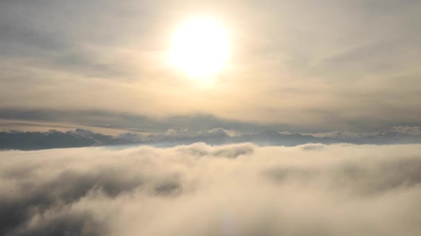Hihetetlen légi felvétel a felhők és a köd fölött, naplementekor a hegyekben. Alacsony felhőfelszín felett repül, háttérben egy gerinccel — Stock videók