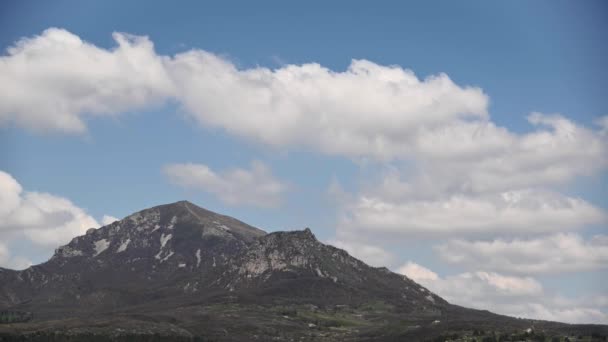 Летнее время над горой с несколькими вершинами, облака плавают, отбрасывая тени на зеленый лес. — стоковое видео