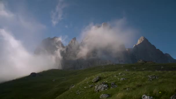 Timelapse Una escena increíblemente hermosa, la cima de una montaña rocosa está cubierta de nubes masivas y se esconde detrás de ellas. Verano. Las laderas están cubiertas de hierba verde fresca — Vídeos de Stock