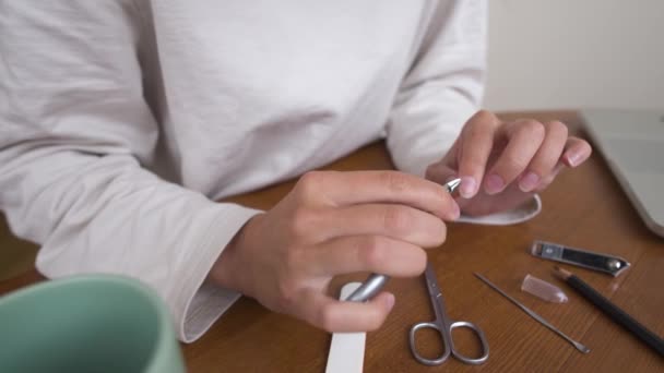 Jeune femme belle caucasienne est assise sur une chaise dans la cuisine à la maison, occupée avec sa routine de beauté, range et beauté ses ongles sur ses mains — Video