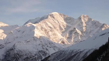 Elle tutulan kar kaplı kayalık dağ zirveleri manzarası. Gün batımında hayat kamerası dağları