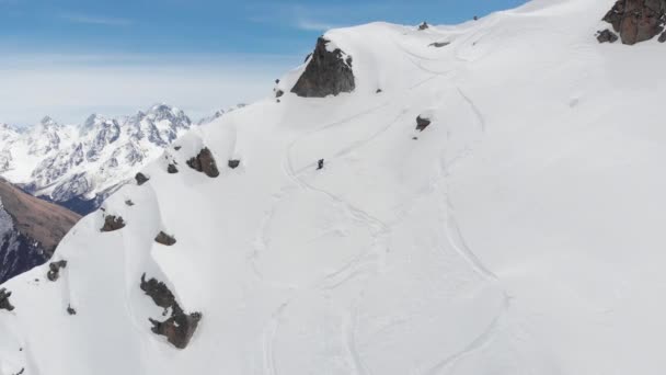 นักกีฬาชายนักสกีสุดขั้วปีนเขาบนความชันที่สูงชันและผงหิมะสูงในภูเขา สกีลงเขา มุมมองทางอากาศฟรีไซด์ — วีดีโอสต็อก