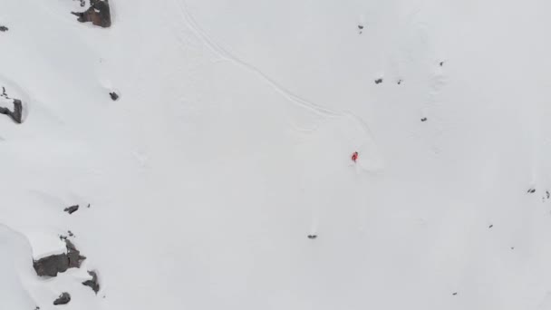 Vista aérea de un esquiador de backcountry montando un freeride en una pendiente empinada. Esquí profesional extremo en las montañas de los Alpes o el Cáucaso Norte — Vídeo de stock