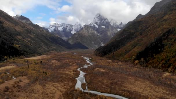 Vallée de montagne d'automne avec une rivière haute dans les montagnes avec de hautes falaises et des montagnes et des nuages épiques en arrière-plan. Vue aérienne du vol au-dessus d'un relief montagneux — Video