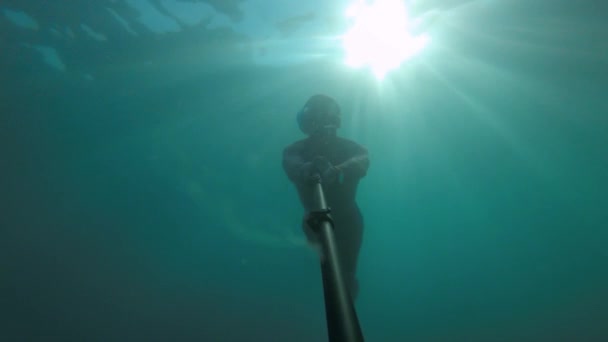 Un homme dans l'eau de mer claire est engagé dans la plongée en apnée et en apnée. Silhouette d'un plongeur nageant en profondeur avec les rayons du soleil par derrière. Film grain en vidéo — Video