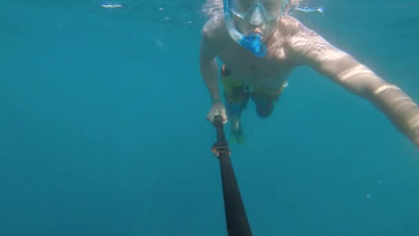 Sportovní mladý muž v masce a šnorchlu s ploutvemi a hlubokými ponory plave pod vodou. — Stock video