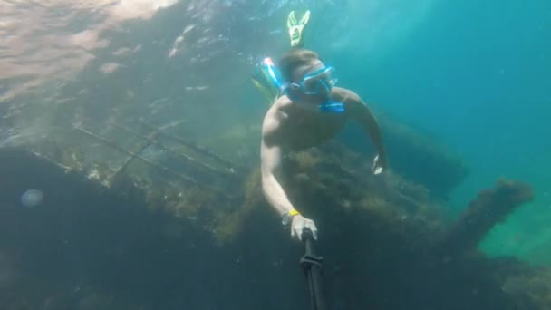 Joven buceo libre en una máscara nada bajo el agua junto a un barco hundido. Cámara de acción selfie stick — Vídeos de Stock