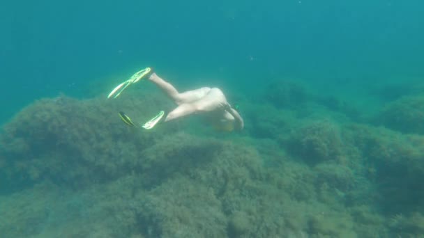 Žena ve žlutých plavkách s šnorchlovou maskou a ploutvemi pluje za slunečného dne přes korálový útes, zastřelena zpomaleným pohybem.. — Stock video