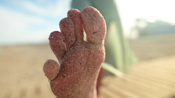 Close-up of foot and toes in the sand of a young girl in slow motion. Wiggles toes on a sandy beach on a sunny day — Stock Video