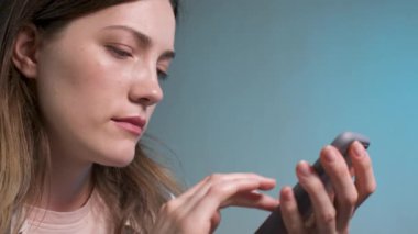 Çekici beyaz bir genç kadının portresi. Masadaki mutfakta oturuyor ve akıllı telefonuyla internetten alışveriş yapıyor..