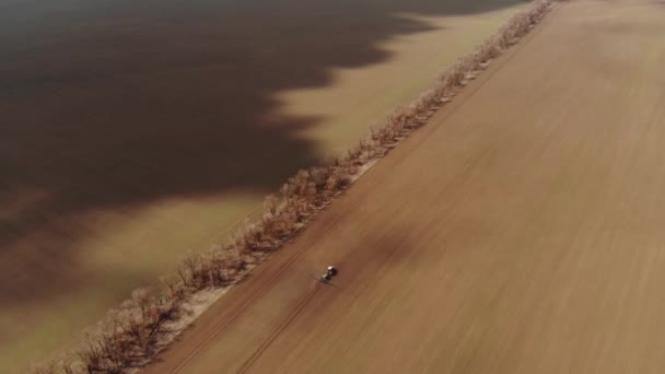 Vue aérienne d'un tracteur agricole pulvérisant un champ avec un pulvérisateur, des herbicides et des pesticides au coucher du soleil. Machines agricoles travaux agricoles saisonniers naturels — Video