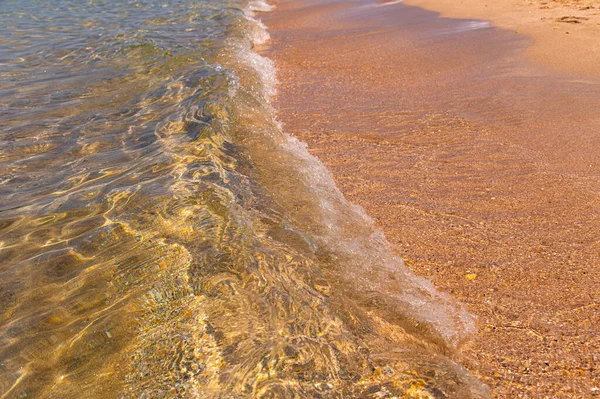 Tiszta tiszta víz a tengerben, napfény, hullámok és tengeri homok. Nyugodt tengervíz háttér — Stock Fotó