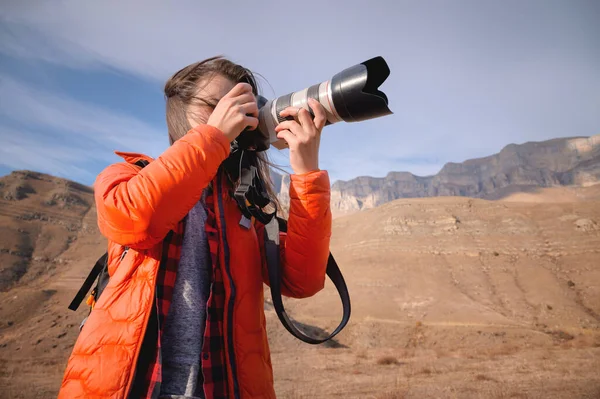 Жінка-пейзажистка з великими об'єктивами і професійна камера фотографує гори на тлі епічних каменів. — стокове фото