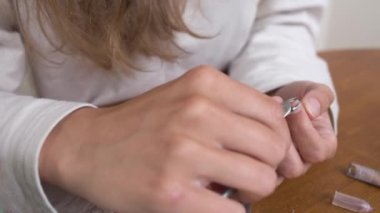 Beyaz, güzel bir kadın evdeki mutfakta bir sandalyede oturuyor, güzellik rutiniyle meşgul, etrafı toparlıyor ve elleriyle tırnaklarını güzelleştiriyor.