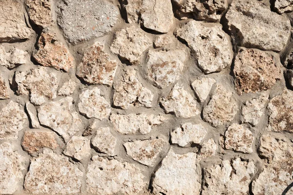 A parede de pedra é forrada com pedra natural e cimentada. Material de construção natural. Fundo medieval — Fotografia de Stock