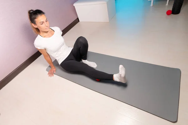 Sporty slim caucasian woman doing self massage on fitness mat with massage ball indoors. Self-isolation massage — Stock Photo, Image