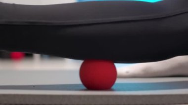 Spor salonundaki bir kadının masaj topunu kullanarak kendine masaj yapması. Masörsüz miyofasyal masaj. Bacak kaslarındaki ağrının giderilmesi