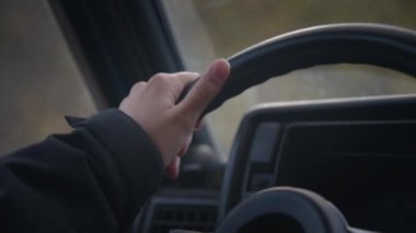 Yakın çekim yaşam çerçevesi, dağlarda giden eski bir arabanın direksiyonundaki beyaz bir kadının elinin canlı görüntüsü.