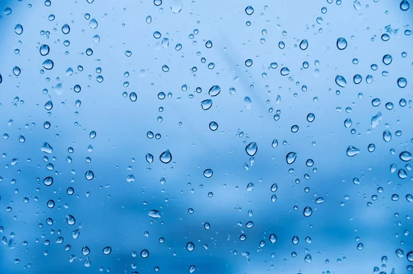 Gotas de chuva em vidro em cores frias. Foco suave fundo frio dia chuvoso — Fotografia de Stock