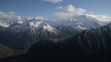 Sırt çantalı genç bir erkek gezgin dağlarda durup batan güneşe bakıyor. Yakın plan.