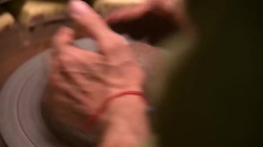 Çömlekçi bir adamın yakın plan çekimi çömlekçi çarkına yerleştirilmek için onu yener.