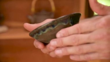 Erkek bir çömlekçi, yakınlardaki el yapımı çay seremonisi için killi çaydanlık yapıyor. Sığ alan derinliği