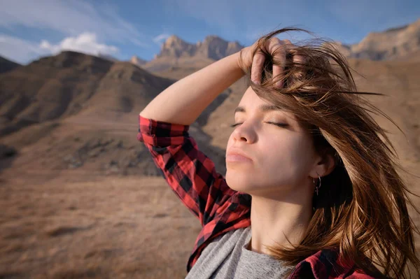 Retrato de mulher jovem caucasiana atraente desfrutando de olhos fechados fica nas montanhas contra o fundo de rochas épicas — Fotografia de Stock