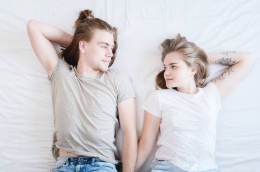 Genç evli bir çiftle kadın yatak odasındaki yatağa uzanıp birbirlerine bakıyorlar. Genç neslin aile hayatı. Yukarıdan görüntüle