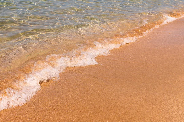 Transparant zeewater. Het gouden zand wordt gewassen door kleine golven helder water met schuim. Mariene achtergrond. toerisme en reizen — Stockfoto