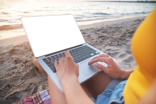 Detailní záběr vystřižené obrazovky notebooku na klíně mladé bělošky sedící při západu slunce na písečné pláži u moře. Místo pro kopírování na volné noze a na dálku — Stock fotografie