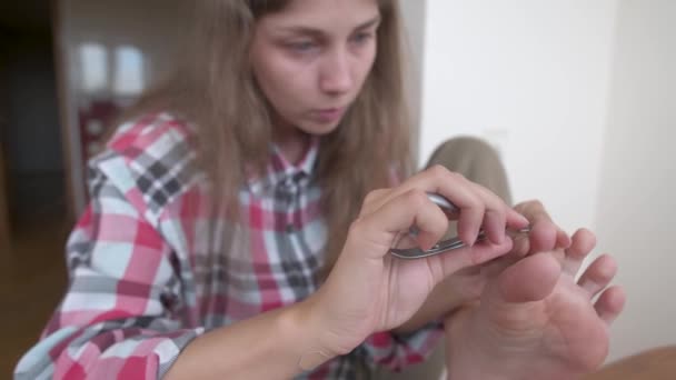 Una giovane donna caucasica si sta facendo una pedicure a casa. Cura di unghie e dita dei piedi. Prendersi cura della salute dei piedi — Video Stock