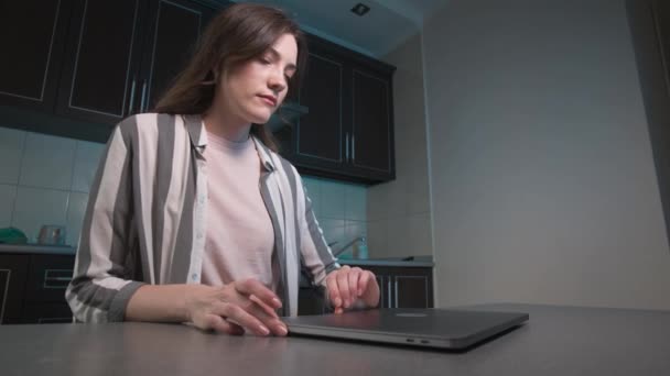 Женщина-фрилансер дома работает над ноутбуком. Кавказская девушка открывает ноутбук и начинает печатать текст, сидя дома за столом на кухне. Крупный план — стоковое видео