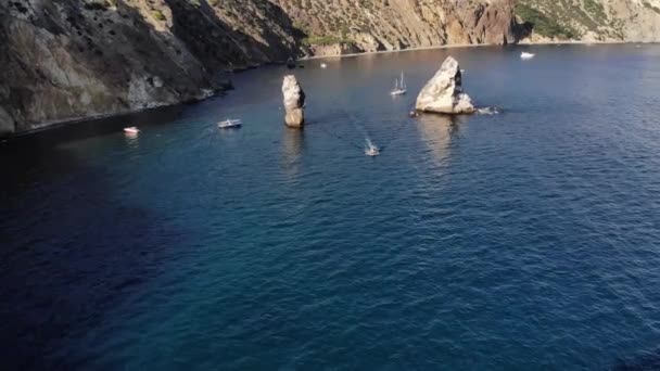 Touristenboote mit Yachten schwimmen an der felsigen Küste zwischen Klippen in einem beliebten Touristenziel. Wassertourismus und Erholung auf See. Touristenbucht — Stockvideo