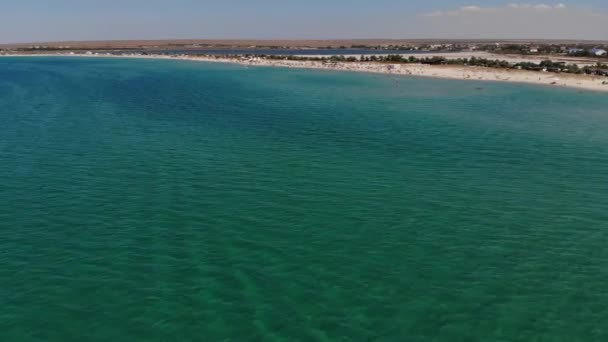 Αεροφωτογραφία μιας τουριστικής παραλίας με ανθρώπους να ξεκουράζονται. Αμμώδης παραλία του παραθαλάσσιου θέρετρου σε μια ηλιόλουστη μέρα. Αναψυχή στην ακτή του ωκεανού — Αρχείο Βίντεο