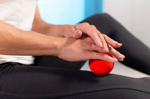 Sportiv femeie caucaziană subțire care face auto-masaj al coapsei pe covorul de fitness cu minge de masaj în interior. Masaj de autoizolare — Fotografie, imagine de stoc
