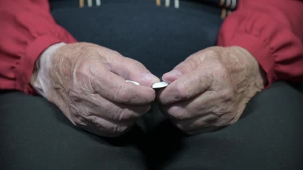 Oude vrouw een oude vrouw met tabletten in handen zittend op een stoel in de kamer. Verwijdert tabletten uit de blisterverpakking — Stockvideo